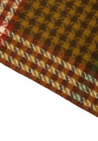 Uldstof med brunt og gult hundetandsmønster, afgrænset af rødt, creme, sort og grønt ternet design.