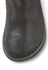 Bota negra texturizada con la punta brillante y suave, y suela de goma, con una forma redondeada. El material parece suave y ligeramente brillante.