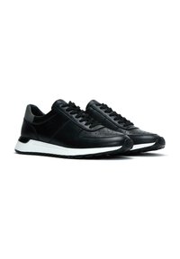 Sneaker nere con un mix di pelle liscia e pelle texturizzata, dettagli perforati, lacci neri e una suola intermedia bianca in contrasto con la suola in gomma.