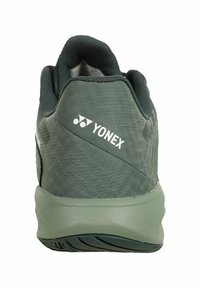 Yonex athletic shoe with a textured dark green upper, white logo on heel, and a smooth green sole featuring a slight pattern for traction.