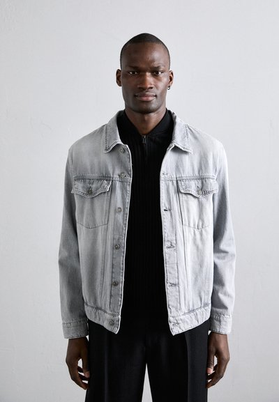 Grijze denimjack met kraag, voorzakken, metalen knopen en een relaxte pasvorm. Draag het over een zwarte ribbeltrui voor een casual uitstraling.