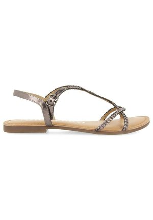 Sandalias planas en tono metálico bronce, con correas trenzadas, hebilla ajustable en el tobillo y una plantilla suave en beige con un diseño de suela mínimamente texturizado.