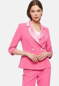 Blazer rosa a doppio petto con revers in satin e maniche a tre quarti, dotato di bottoni rotondi e vestibilità sartoriale.