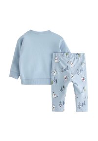 Jasnoniebieska bluza z długim rękawem, w zestawie z jasnoniebieskimi legginsami z wesołym wzorem drzew i postaci. Miękka tekstura.