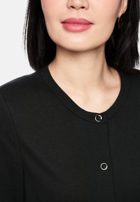 Schwarzer Cardigan mit rundem Ausschnitt und zwei vorderen Knöpfen. Der Stoff hat eine glatte Textur, mit einem figurbetonten, klar geschnittenen Design.