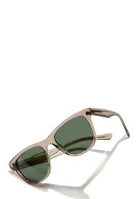 Ochelari de soare tip cat-eye cu un cadru transparent de culoare maro deschis și lentile verde închis. Caracteristicile includ brațe drepte și detalii subtile ale mărcii.