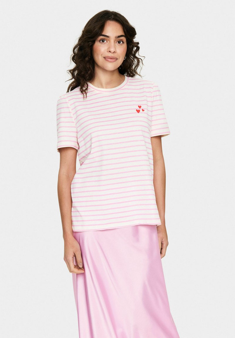 T-shirt rayé rose et blanc en tissu doux, avec un col rond, des manches courtes et une broderie de cœur rouge sur la poitrine gauche.