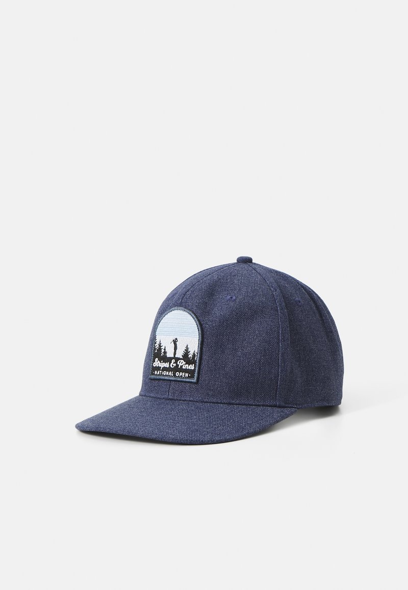 Casquette bleu marine en tissu texturé, ornée d'un emblème rond avec des arbres et un golfeur. Une visière incurvée achève le design.