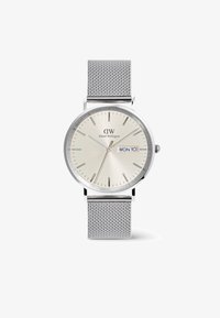 Reloj con correa de malla plateada, esfera redonda de un dorado claro, marcadores de horas, indicador de fecha y el logotipo de la marca en la parte superior.