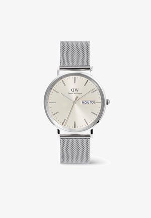 Ezüst hálós szíjas óra kerek, világos arany számlappal, órajelzőkkel, dátum kijelzővel és a márka logójával a tetején.