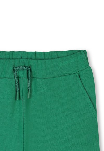 Groene sportbroek met een gestructureerde afwerking, voorzien van een trekkoord tailleband en zijzakken. Het materiaal lijkt zacht en comfortabel te zijn.