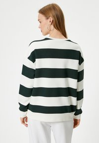 Felpa a righe verdi e bianche con scollatura tonda e maniche lunghe. Presenta una vestibilità rilassata e un tessuto morbido e strutturato.