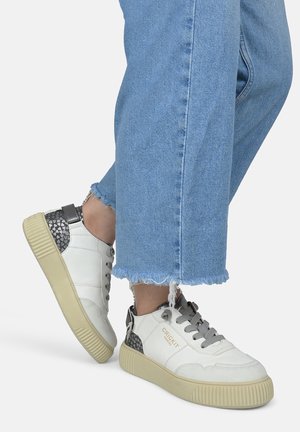 Witte leren sneakers met grijze accenten, gestructureerde hak en lichtgekleurde rubberen zool. Gedragen met blauw jeans met rafelige zoom.
