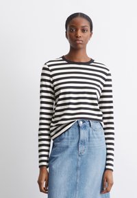 Schwarz-weiß gestreiftes Langarmshirt mit einem runden Halsausschnitt, getragen über einem hellblauen Denimrock. Klassisches Design mit lässiger Passform.