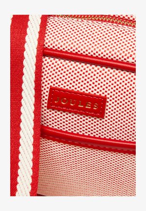 Rot-weißes strukturiertes Gewebe mit einem roten Lederlogo-Patch mit der Aufschrift "JOULES" und einem roten Reißverschlussdetail.