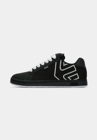 Schwarze Sneakers im Low-Top-Design mit weißen Schnürsenkeln, weißem geometrischem Logo an der Seite, "etnies"-Tag und schwarzer Sohle mit "etnies"-Branding.