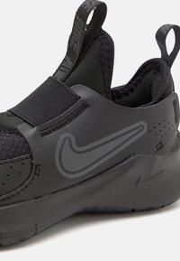 Fekete sportcipő, amely slip-on kialakítással, elasztikus pánttal, textúrált anyaggal és egy diszkrét Nike logóval rendelkezik az oldalán.