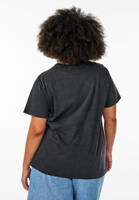 Camiseta de algodón negra de manga corta, con un cuello redondo y un corte relajado. La tela tiene una ligera textura y un acabado desgastado.