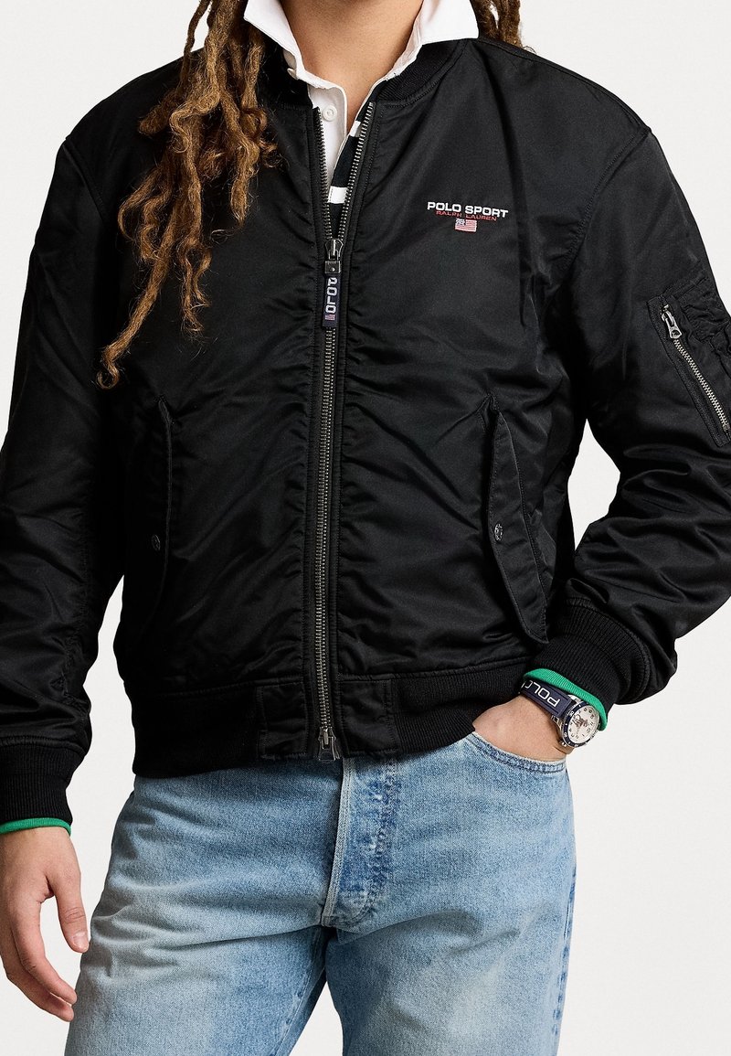 Svart bomberjacka med dragkedja, ribbade ärmar och krage. Har "POLO SPORT"-logotyp på bröstet och sidofickor. Texturerad tyg.