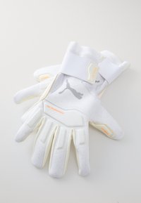 White goalkeeper gloves with textured latex palms, reinforced finger sections, and an adjustable wrist strap. Features a gray logo and orange accents.