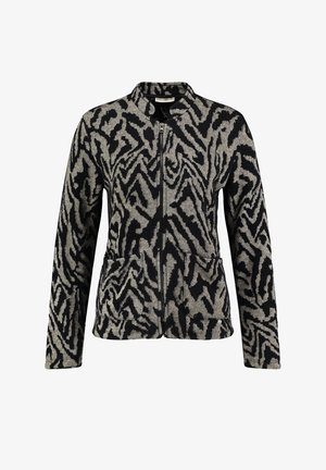Chaqueta con cremallera en negro y crema, con un patrón asimétrico de zigzag texturizado, que cuenta con bolsillos laterales y un diseño de cuello alzado.
