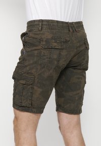 Tarnfarben Cargo-Shorts aus olivgrünem Stoff, mit mehreren Taschen, einem elastischen Bund und einer strukturierten Oberfläche mit dezenten Mustern.