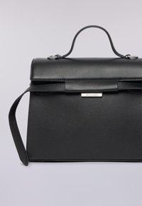 Černá kožená kabelka se strukturovaným designem, plochým víkem a krátkým držadlem. Obsahuje stříbrnou logovou desku a odnímatelný popruh.