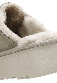 Suède instapschoen met een pluche beige bontvoering, een gestructureerde beige platformzool en een gladde beige rand rond de opening.