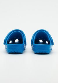 Modré gumové dřeváky s otevřenou patou, texturovanou stélkou a ventilačními otvory. Silné podrážky s vzorovaným dezénem pro lepší grip.