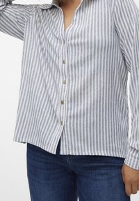 Gestreept overhemd met knopen in wit en blauw, met een V-hals, lange mouwen en een losse pasvorm. Heeft knopen aan de voorkant en een zachte stoftextuur.