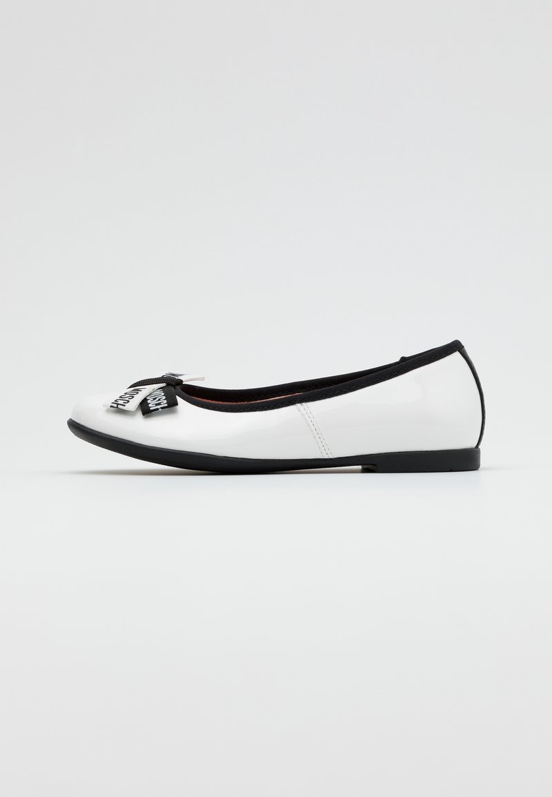 Ballet flat en cuir verni blanc avec une semelle noire et un accent en nœud de ruban avec texte imprimé. Texture lisse, design à bout rond.