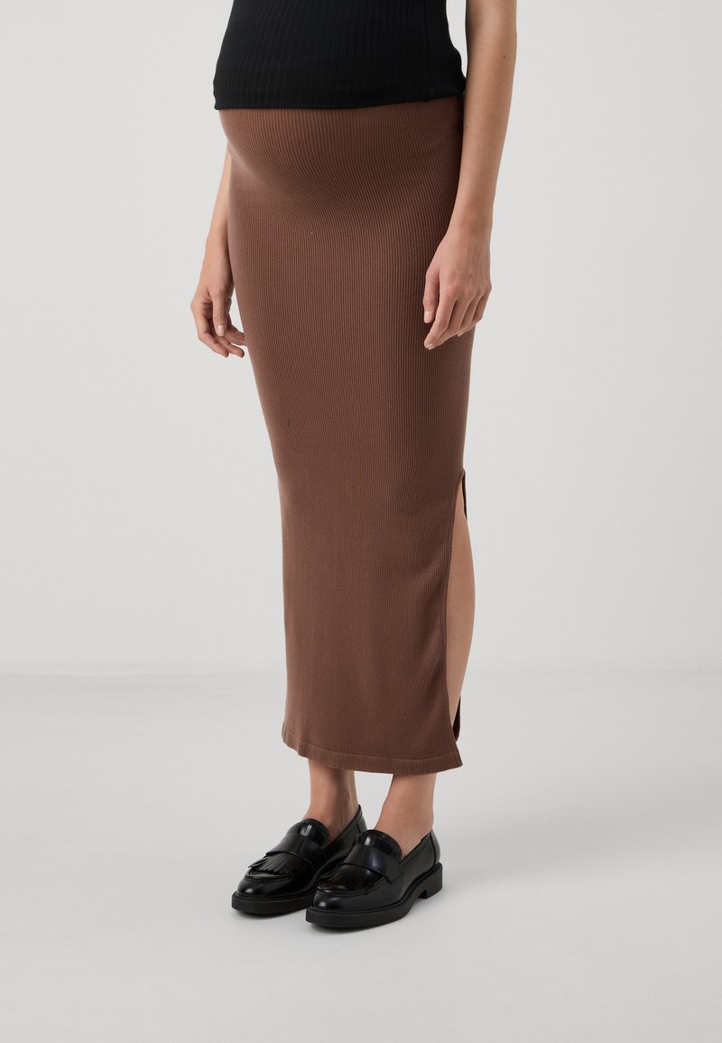Brun ribbad maxi kjol med sidslitsar, matchad med svarta loafers. Outfiten har en formad midjeband för en snug passform.