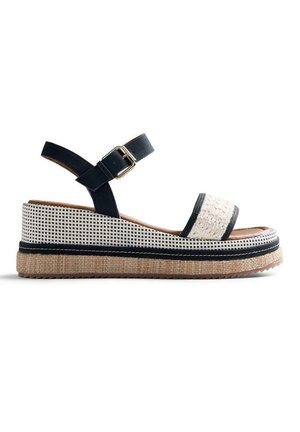 Sandalo con zeppa con cinturino anteriore beige strutturato, cinturino alla caviglia nero con fibbia dorata, zeppa a quadri bianco e nero e strato di suola intrecciato.