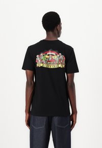 Schwarzes Baumwoll-T-Shirt mit einem bunten Grafikdruck auf dem Rücken, der Skelette und den Text "SANTA CRUZ" in einem dekorativen Banner zeigt.