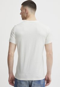 Hvid kortærmet t-shirt lavet af bomuld, med en rund halsudskæring og en glat tekstur. Lidt tætsiddende form bagpå.