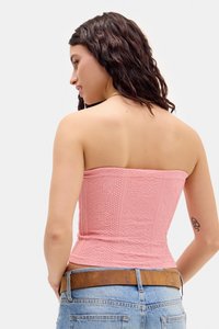 Top cropped rose sans bretelles avec des motifs floraux et géométriques texturés, design ajusté et tissu lisse. Associé à un jean en denim bleu clair.
