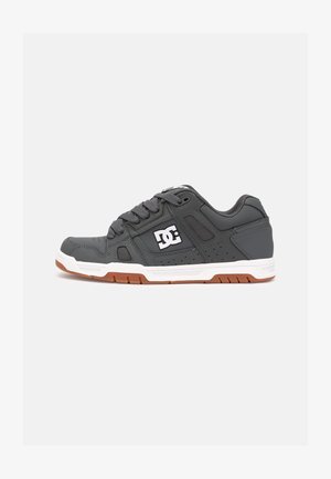 Sneaker gri cu partea superioară din piele, talpă intermediară albă, talpă exterioară din cauciuc maro și detalii perforate. Prezintă logo pe lateral și șireturi texturate.