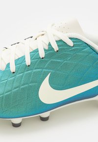 Scarpa da calcio in teal e bianco, con tomaia sintetica texturizzata, motivo a rombi, lacci bianchi e dettagli neri sui tacchetti.