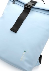 Modrý voděodolný batoh s rolovacím vrškem, černým popruhem a sponou. Obsahuje logo v zelené a bílé barvě, vyrobený z recyklovaných materiálů.