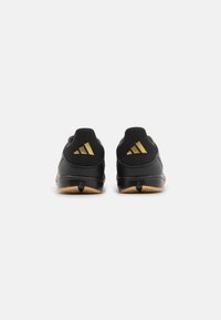 Zapatillas deportivas negras con un upper texturizado, que presentan franjas doradas en el talón y una suela de goma de color contrastante.
