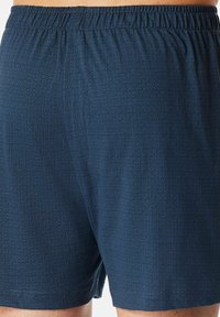 Boxer da uomo in un tessuto blu scuro con un motivo geometrico. Vita elastica, materiale leggero con una sottile texture.