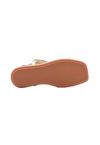 Sandal di colore beige con suola in gomma testurizzata e dettagli metallici decorativi. Il design delle cinghie presenta un motivo a incrocio.