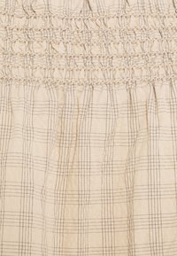 Abito beige elasticizzato con corpino arricciato e tessuto raccolto, caratterizzato da motivi a quadri scuri. Materiale in cotone morbido e texturizzato.