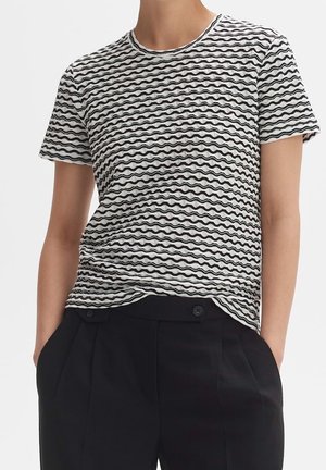 Maglietta bianca e nera con motivo a onde, maniche corte, scollo rotondo e una morbida texture, abbinata a pantaloni neri a vita alta.