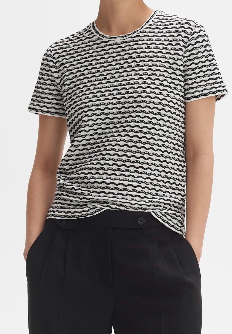 Zwart-witte t-shirt met een golfpatroon, korte mouwen, ronde halslijn en een zachte textuur, gecombineerd met zwarte high-waisted broek.