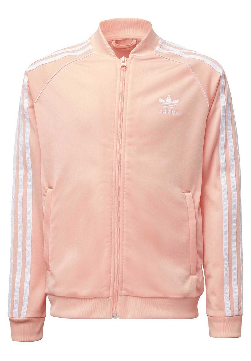 Vaaleanpunainen Adidas-urheilutakki, jossa on koko matkalta vetoketju, resorit kauluksessa ja hihojen suissa, kaksi sivutaskua sekä valkoiset kolmen raidan yksityiskohdat hihoissa.