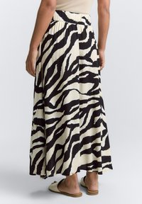 Maxi-Rock in Creme mit schwarzen Zebra-Streifen, aus leichtem Stoff, mit einem plissierten Design und einem elastischen Bund.