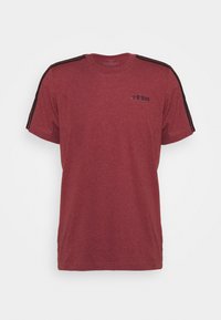 Camiseta de algodón roja con mangas cortas, rayas de acento negras en los hombros y un sutil logo en el pecho. Diseño clásico de cuello redondo.