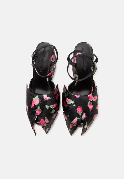 Sandales noires à bout ouvert avec brides à la cheville, motif floral de roses roses et brides croisées pointues en forme de pétales à l'avant.