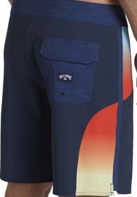 Shorts de baño en color marino con una cinturilla texturizada, que presentan un diseño degradado de rojo a amarillo en el lateral, y un bolsillo trasero con un parche de logo.